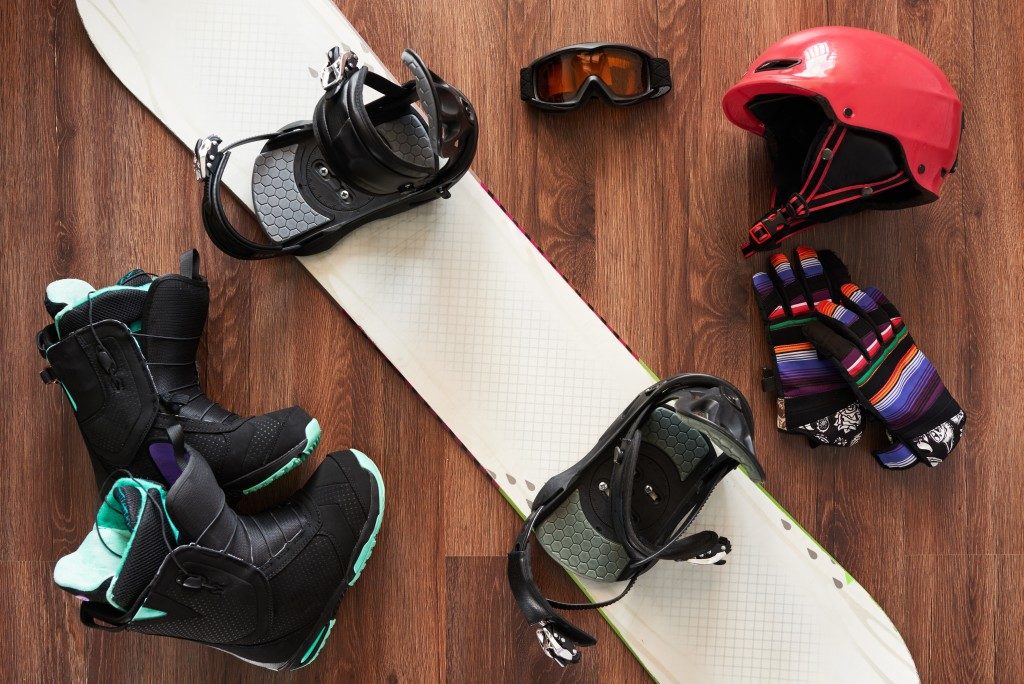 set of snowboard equipment boots, helmet, gloves and mask on a wooden floo