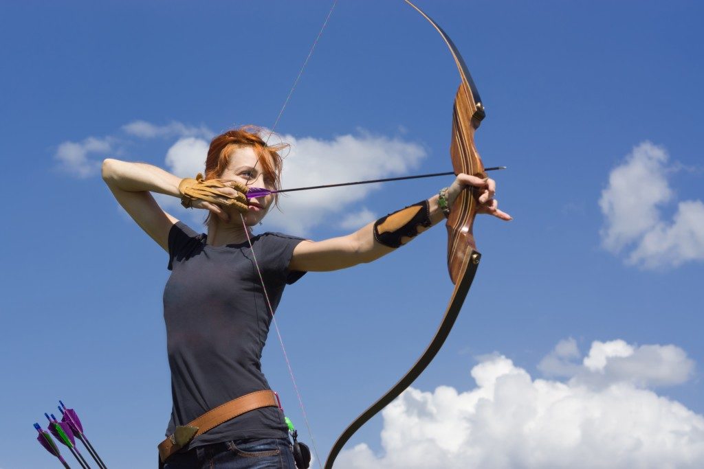 Woman practicing archery in the field