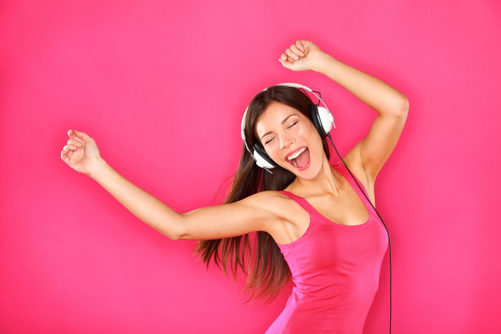 Woman dancing in pink background with headphones