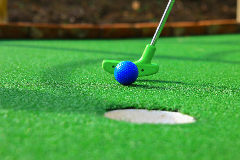 A blue golf ball, a putter, and a golf hole