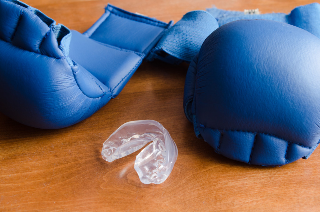 Blue boxing gloves an a mouthguard on the floor