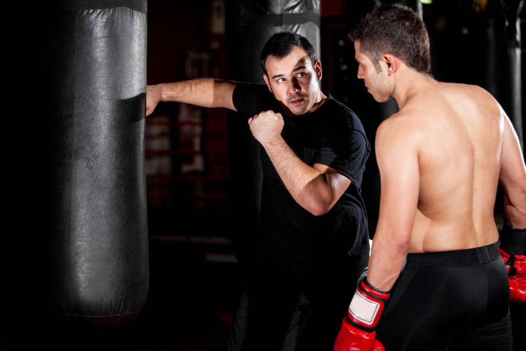 A boxing coach teaching a boxer to punch a punching bag